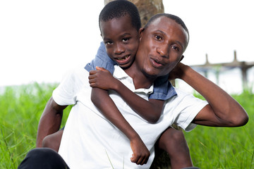 young man sitting in the grass with his little brother.