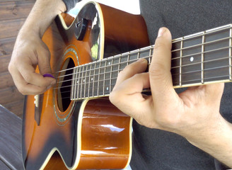 Obraz premium Acoustic guitar. A man plays an acoustic guitar with two hands close-up picture
