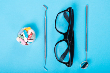 Dentistry set of tools glasses and cup of pills.