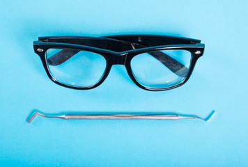 Dentistry toll and pair of black glasses.