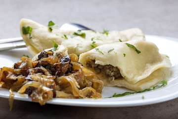 Pierogi, pyrohy or dumplings, filled with beef meat served with fried onion