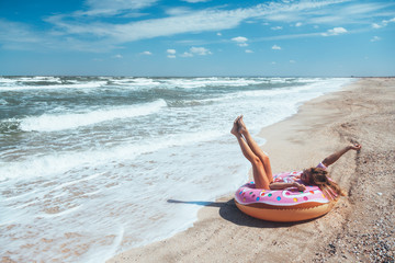 Girl relaxing on donut lilo on the beach