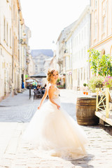 Obraz premium The bride in a cute dress is walking along a beautiful city street on a beautiful sunny day