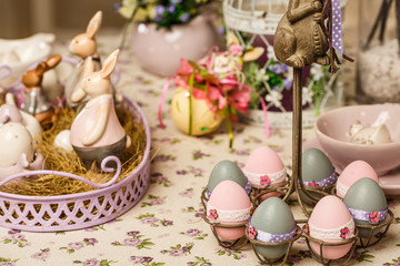 Fototapeta na wymiar Easter breakfast table with tea,eggs in egg cups, spring flowers in vase and Easter decor