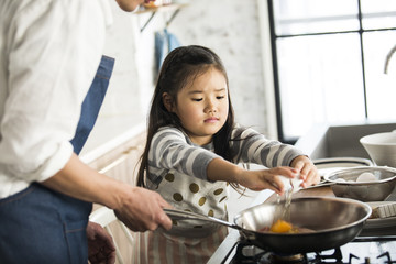フライパンに、女の子が卵を割り入れる。目玉焼き。お手伝い。