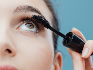 Woman applying mascara on her lashes