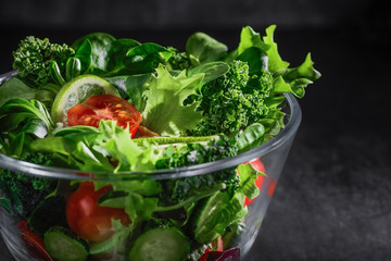 Close-up of fresh vegetable salad over textured dark grey background. The concept of organic vegetarian food.