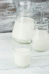 Milk in the glass jugs on the wooden background