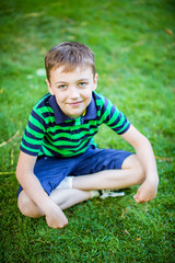 Happy boy sitting in grass in summer