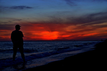 Fototapeta premium Sunset over lake or sea and the silhouette of man