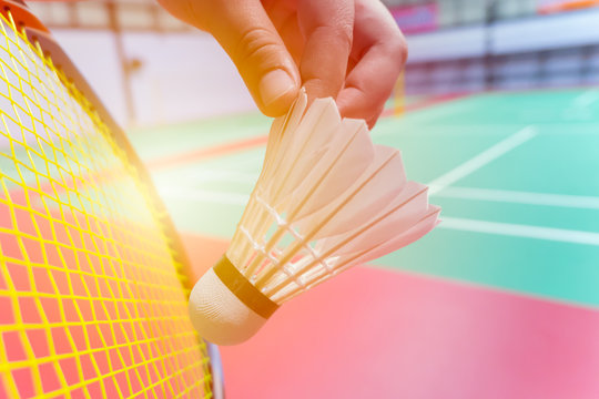 Close Up Hand Hold Serve Badminton Shuttlecock With Blur Badminton Court Background