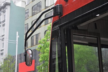 front of red bus in sideview while raining