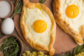 Khachapuri on a wooden texture with spices. Traditional Georgian cuisine.