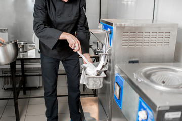 Chef getting white ice cream from the ice cream maker machine in the small manufacturing