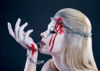 girl with a bloody face, with white skin and a wreath on her head. barbed wire © Sergey