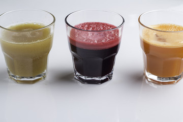 carrot, apple and beet juice on white background closeup.