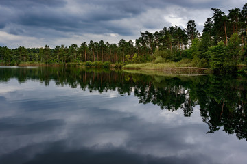 Fototapeta na wymiar Ein dramatischer Wolkenhimmel spiegelt sich im Tonsee im Naturpark Dahme-Heideseen bei Groß Köris