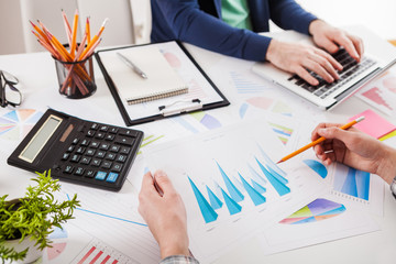Business people discussing the charts and graphs showing the results of their successful teamwork.  Stock market chart and finger pointing on tablet in office.