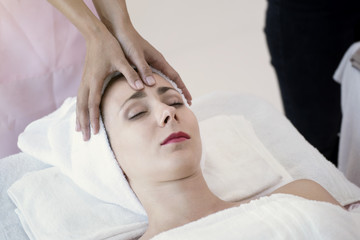 Fototapeta na wymiar Masseur doing massage the head of beautiful young woman relaxing in the spa salon.