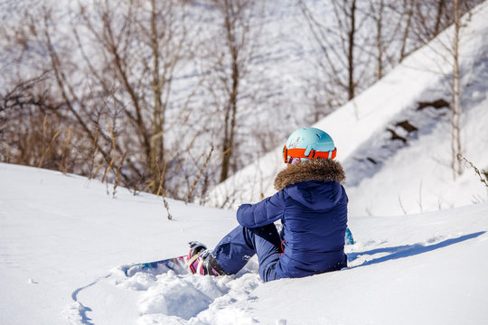 Image from back of athlete in helmet sitting on snowy slope
