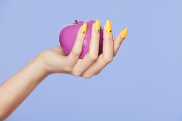 Fototapeta premium Nails Design. Female Hands With Colorful Nails Holding Apple