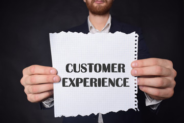 In the hands of a businessman a scrap of paper with the inscription:CUSTOMER EXPERIENCE