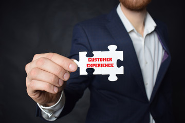Businessman holding a puzzle with the inscription:CUSTOMER EXPERIENCE