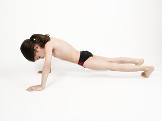 Obraz premium Young sporty guy doing push ups, fitness boy working out plank exercise on hands for body sculpt, four-limbed staff yoga pose on a light background, motivated kid enjoys pilates training on floor