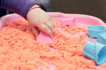 The hands of a child playing with kinetic sand