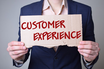 A businessman holds a cardboard with an inscription:CUSTOMER EXPERIENCE
