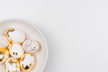 White Easter eggs decorated with golden foil in white bowl. Isolated on white background. Flat lay, top view. Easter concept.