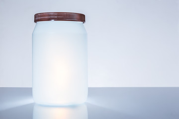 White plastic jar with brown plastic lid on white table