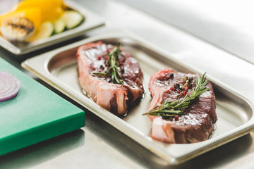 raw meat with herbs and oil on tray on table