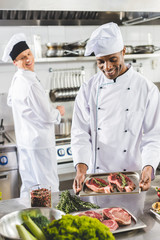 happy multicultural chefs cooking steaks at restaurant kitchen