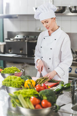 attractive chef cutting vegetables at restaurant kitchen