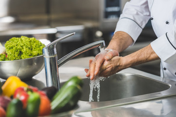 cropped image of chef washing hands at restaurant kitchen