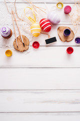 Easter eggs, paints, brushes and palette on the white wood background. Copy space and flat lay