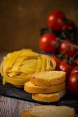 Few pieces of bruschetta next to tagliatelle and cherry tomatoes