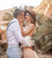 Bride and groom stand, hug and smile in canyon against background of rocks. Closeup.