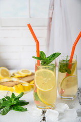 Cold refreshing summer drink with lemon and mint on wooden background
