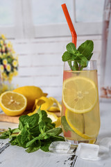 Cold refreshing summer drink with lemon and mint on wooden background