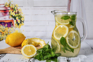 Preparation of the lemonade drink lemonade in the jug and lemons with mint on the table