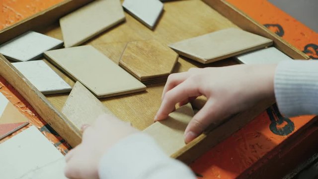 Close-up, hands of a child playing with a wooden puzzle. Concept of education.