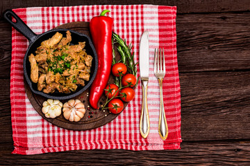 Fried pork in frying pan and vegetables
