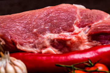 Raw pork steak with pepper, herbs and tomatoes