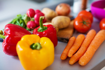 Close up of fresh diverse colorful vegetables being washed and prepared to be cooked on a kitchen counter.
