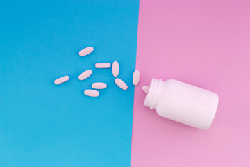 Light pills and a white bottle on a bright colored background. Pills on a pastel pink and blue background
