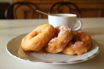 fried donuts with honey and coffee on the table