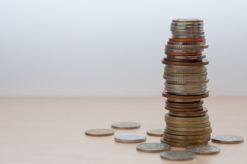 A high stack of coins of different countries, color, dignity and size. Around her coins are...