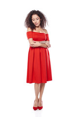 Beautiful curly female in red dress and red high heels shoes in full length looking down posing